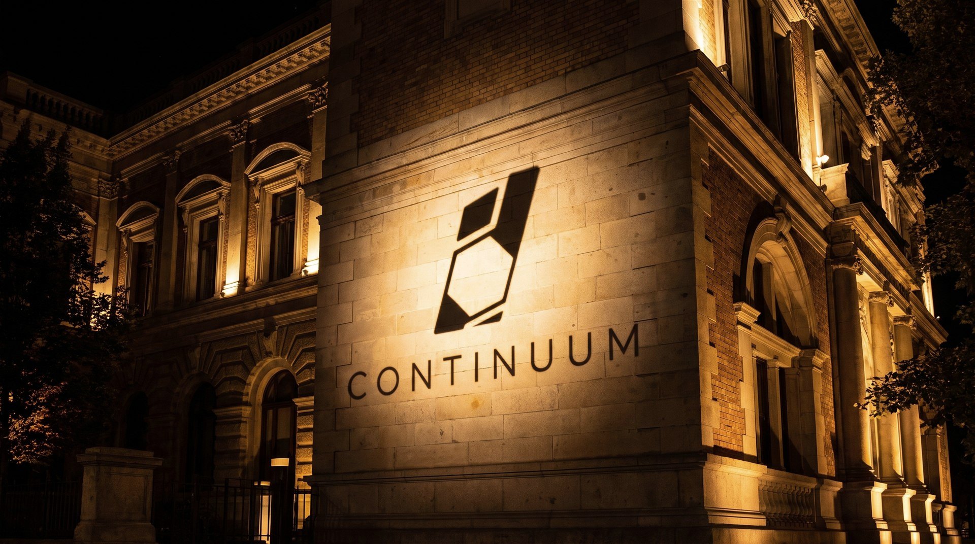 Façade architecturale en pierre éclairée de nuit portant l’emblème et le nom Continuum.
